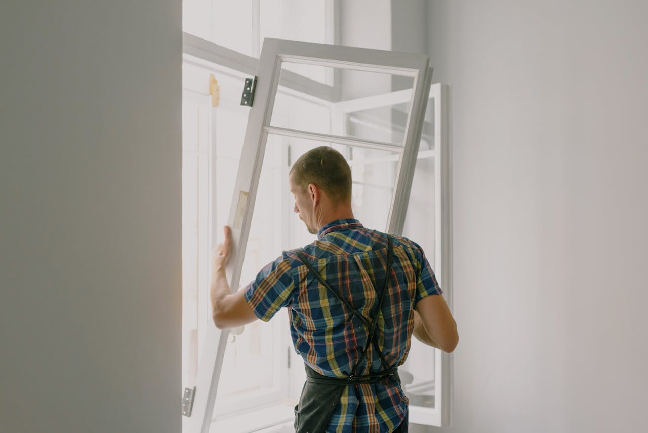 services-03 A professional installer fitting a modern window in a well-lit home interior.