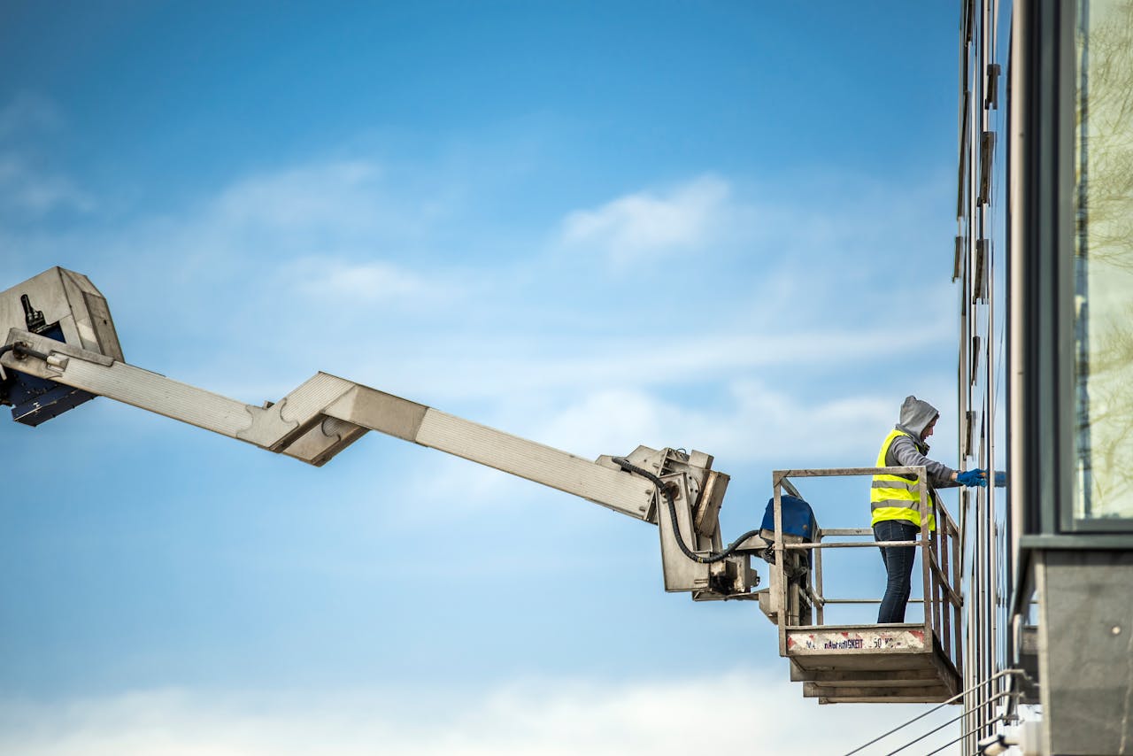 about-02 A construction worker cleans glass windows on a high-rise building using an industrial lift.